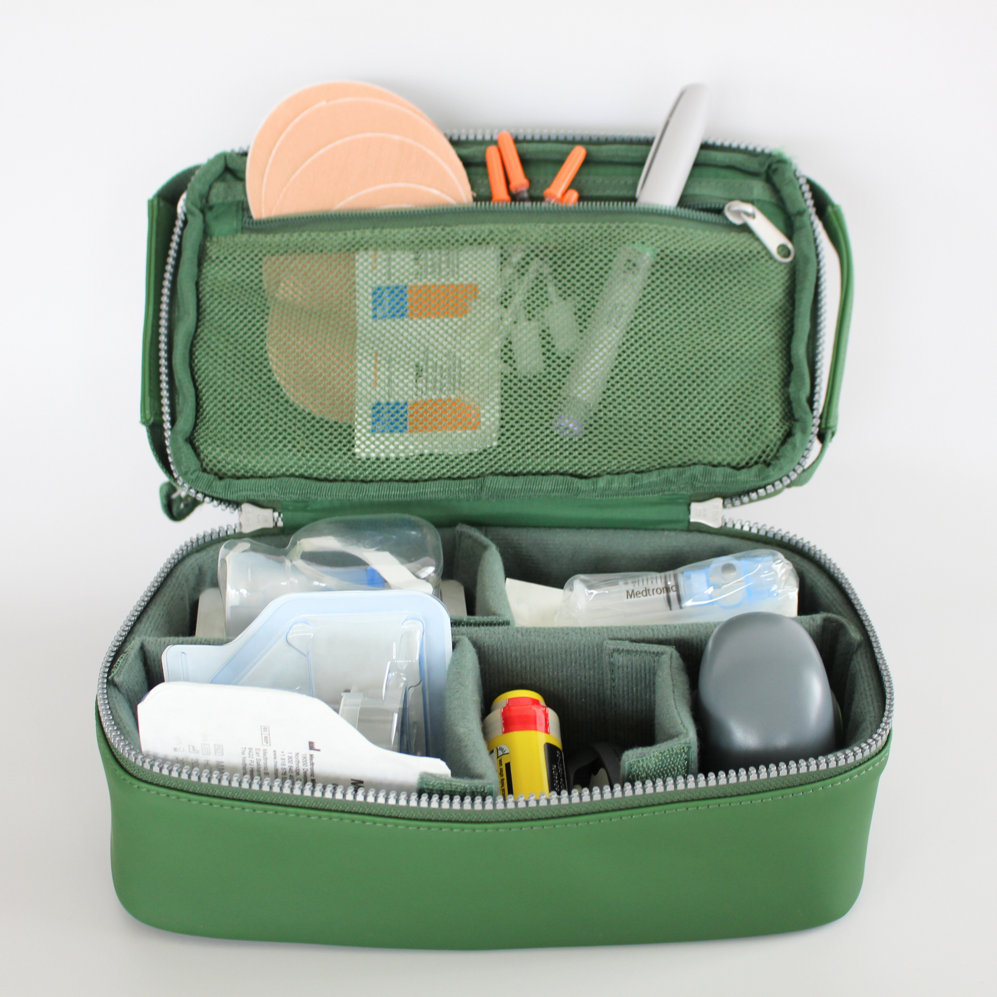 Green diabetes travel bag with various diabetes supplies on a light gray background