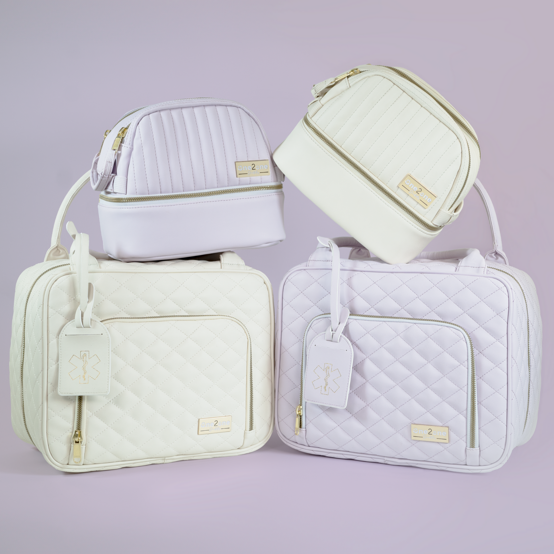 Two small diabetes travel bags in lavender and white stacked on top of two large diabetes travel bags in lavender and white on a purple background.